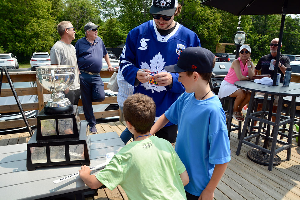 Blake Smith, of the Calder-Cup-winning Toronto Marlies, signed plastic hockey sticks for a pair of fans during a stop-over with the cup at Creekside Golf in Grafton. /Alan Rivett photo