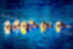 Row of ducklings swimming in deep blue water