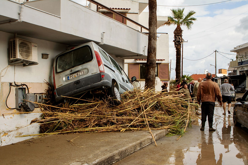 People gather in a mud-covered street with a damaged car following floods caused by storm Bora in the area of Lalysos, on the island of Rhodes, Greece, December 1, 2024. Lefteris Damianidis