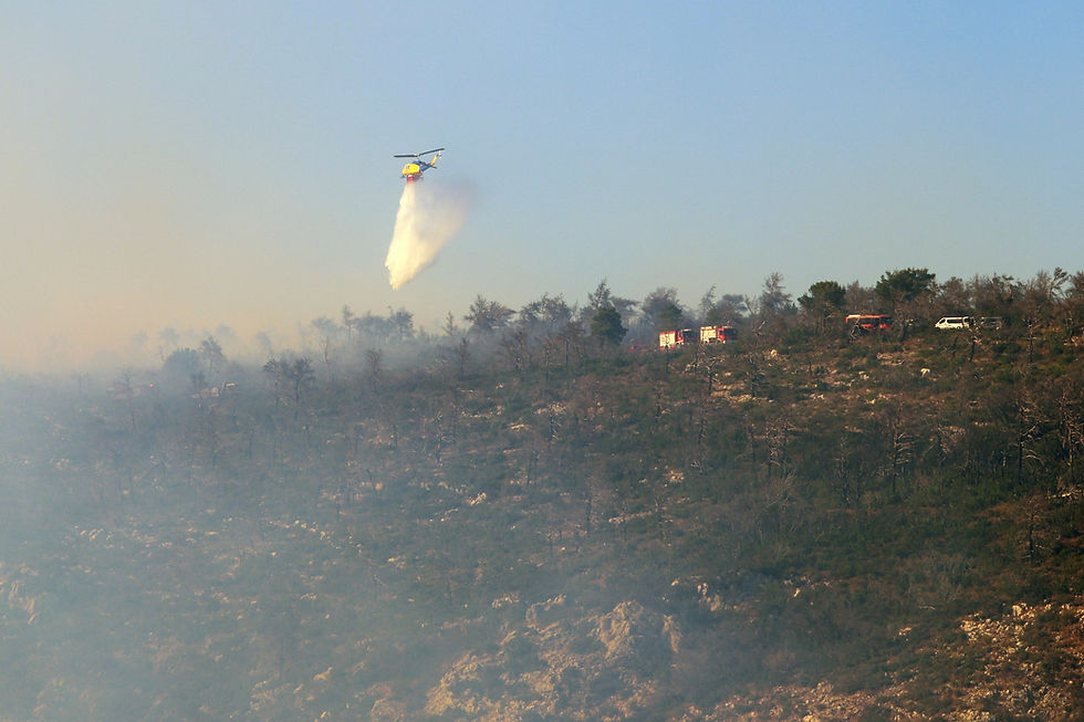 A firefighting helicopter drops water as a wildfire burns on Mount Parnitha, near Athens, Greece, June 29, 2024. REUTERS/Elias Marcou