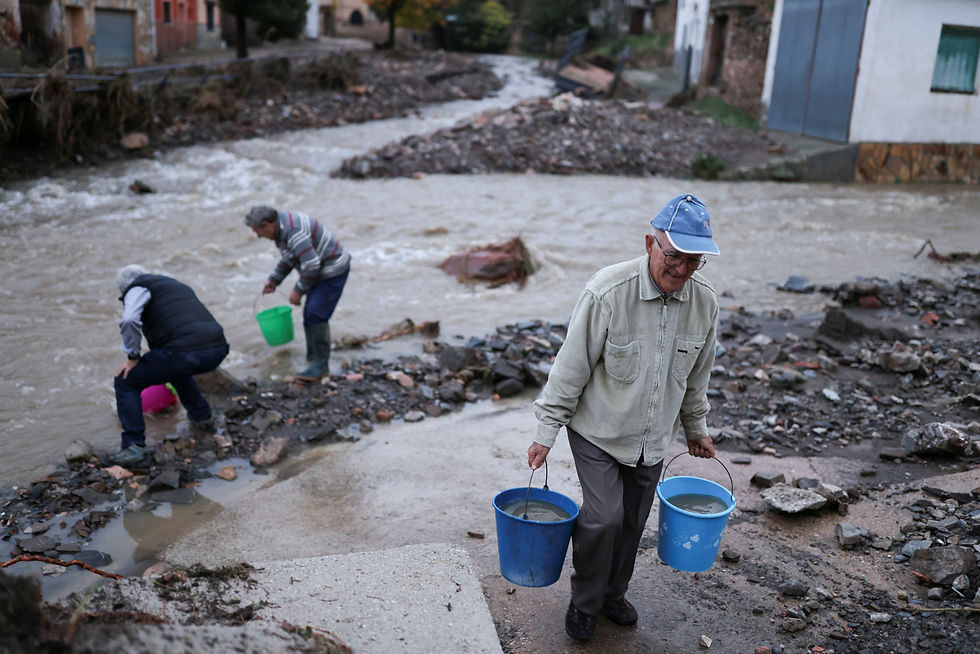 Victoriano, 84, carries buckets of water that he collected from the Dry River (Rio Seco) to clean his house next to his neighbours, after heavy rains caused flooding, in La Hoz de la Vieja, Teruel province, Spain October 30, 2024. Nacho Doce
