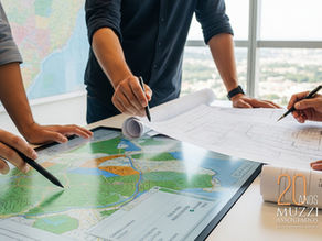 Profissionais analisando mapas e plantas técnicas sobre uma mesa, em ambiente corporativo, representando o trabalho jurídico e técnico do Muzzi Associados em regularização fundiária e direito imobiliário.