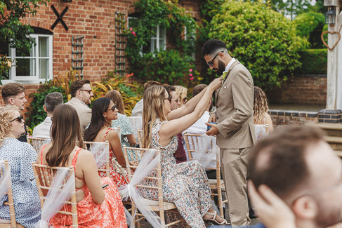 Groom having boutonnière adjusted at Mythe Barn wedding