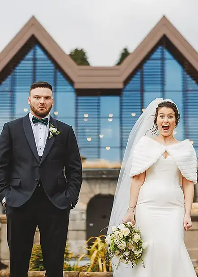 bride and groom outside of hotel pulling faces
