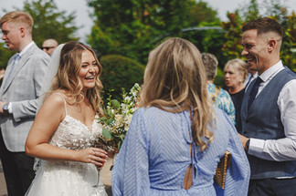 Bride Kate laughing with guests at Mythe Barn wedding.