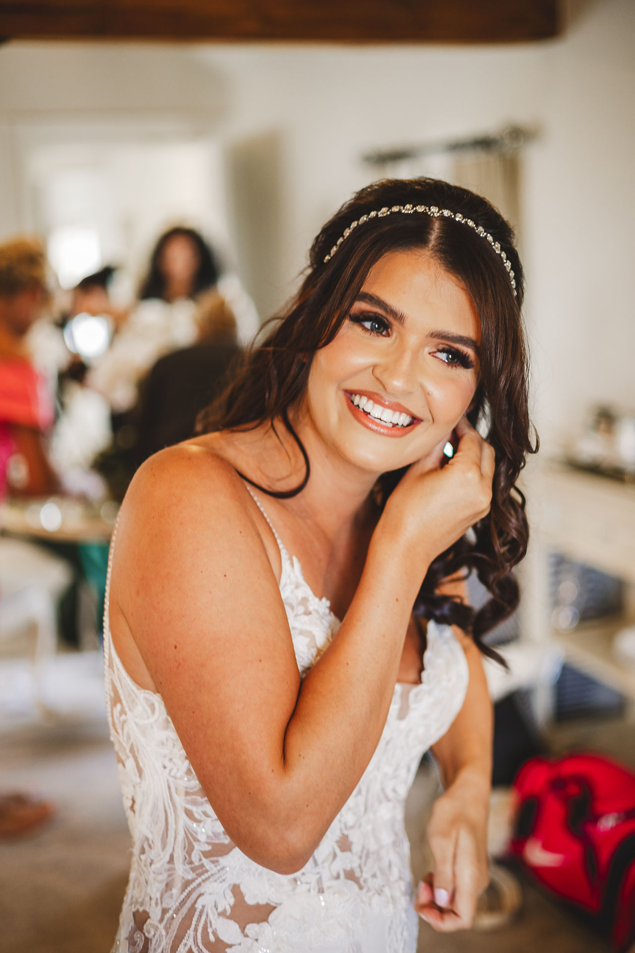 Smiling bride adjusting earring on wedding day, beautiful dress and background. Craig Hickey Photo