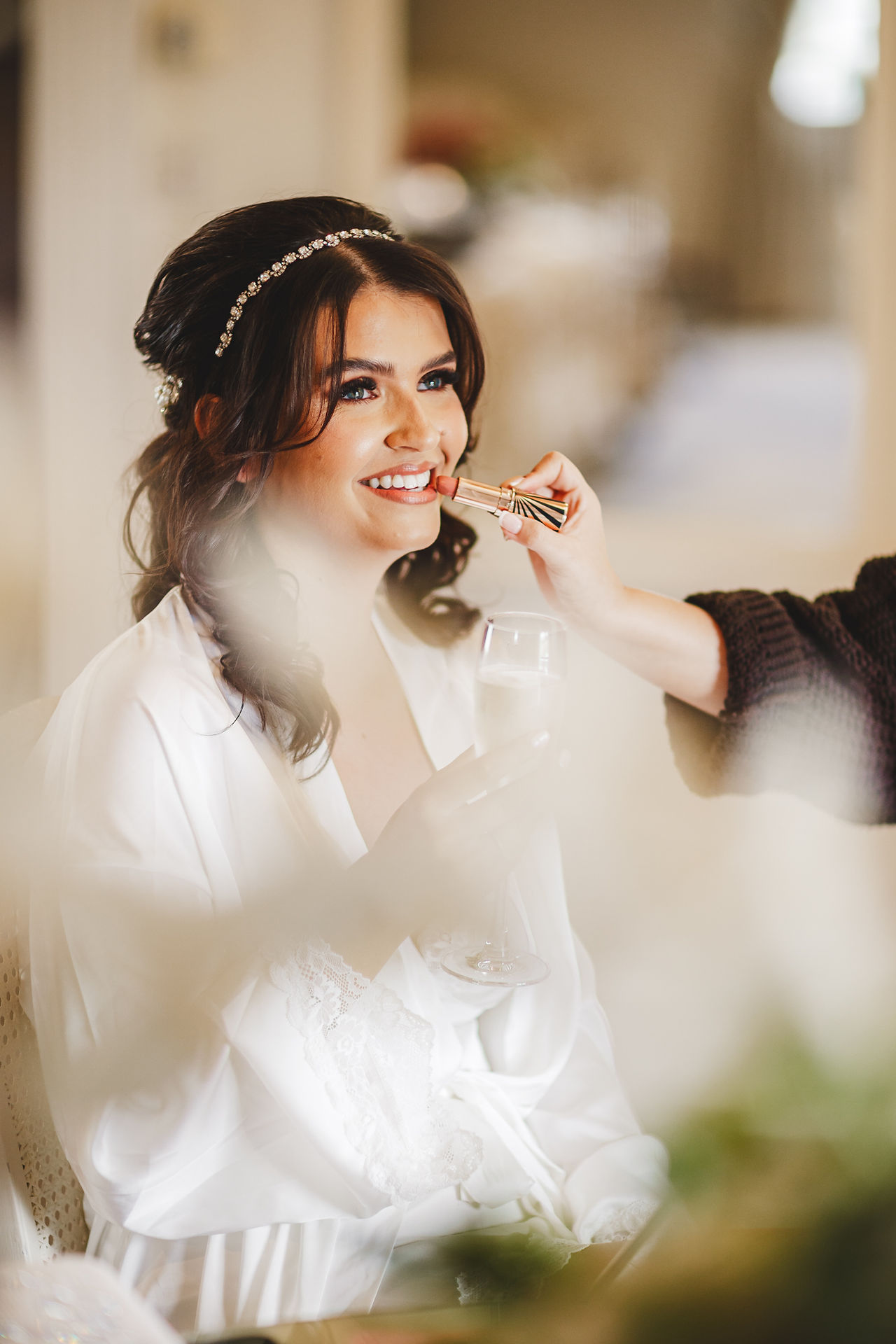 Bride smiles as makeup artist applies lipstick, getting ready. Craig Hickey Photo