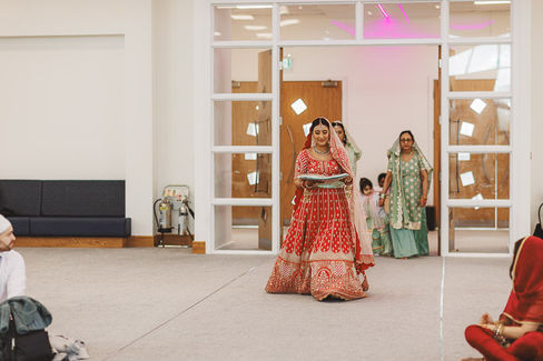 Bride in red lehenga walks into the ceremony during her wedding Craig Hickey Photo