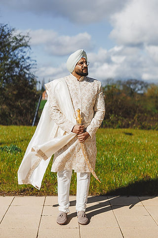 Groom in traditional attire poses outdoors with sword; Craig Hickey Photo.