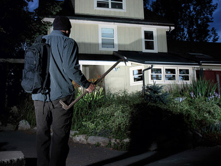 Burglar outside house with security floodlighting