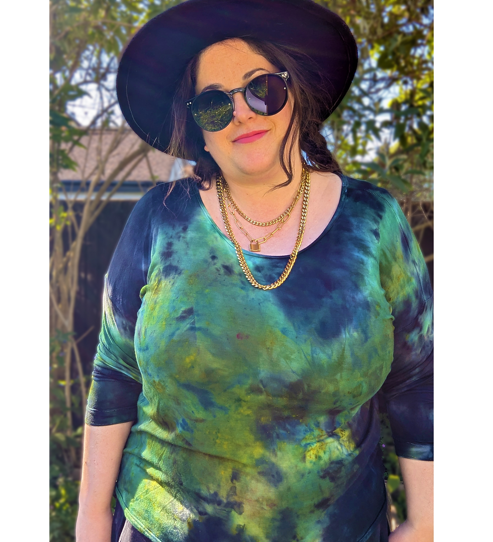 Thumbnail: A mid-size model wears a watercolour, ice dye, tie dye top in blue, green and black it is styled with a black hat