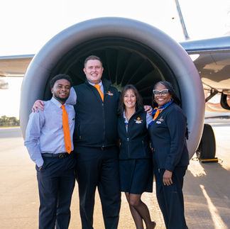 Group of flight attendants standing in front of aircraft engine