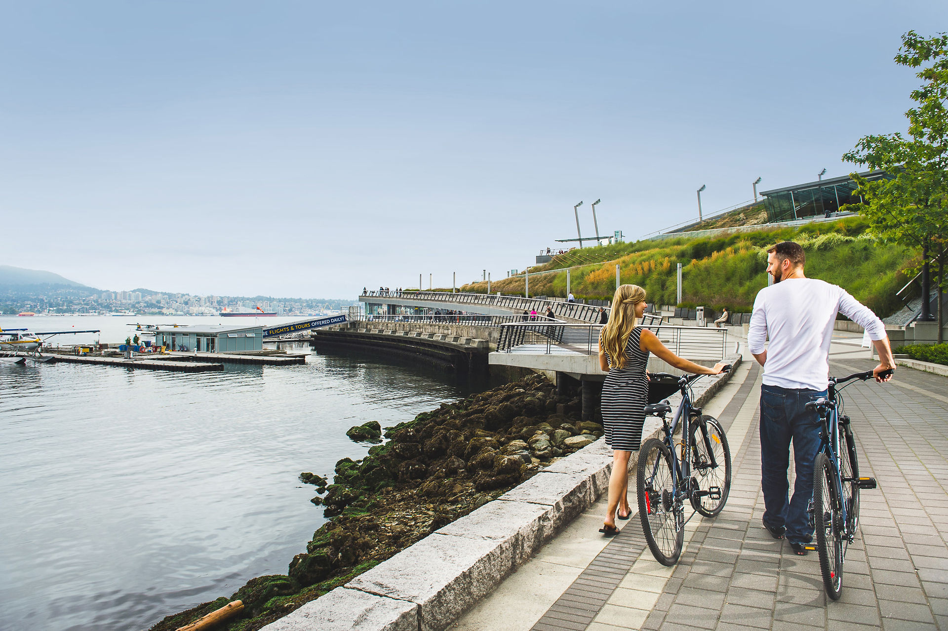 Couple walking with bikes on seawall.