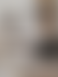 Modern heritage western bedroom featuring a neutral upholstered bed, vintage wooden armoire, dark wood dresser, leather bench, plaid pillows, ceramic vessel, and warm table lamp styled with a collected, nostalgic aesthetic.