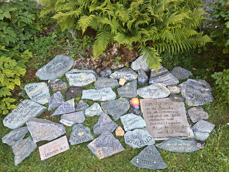 Mehr als 35 „Steine der Erinnerung“ sollen am Semmering an Menschen erinnern, die einst hier lebten und durch die Shoah vertrieben, verfolgt und ermordet wurden. Nun wurde für diese Steine ein besonderer Platz an der Semmeringer Hochstraße gefunden. Zwischen zwei Farnbüschen vor dem Semmeringkircherl liegen schlichte Steine. In Schwarz und Gold beschriftet, tragen sie Namen – und damit die Erinnerung an Menschen, deren Leben mit dem Semmering verbunden war. Gestaltet hat die „Steine der Erinnerung“ Heidelinde Prüger. Als Lyrikerin und Erzählerin beschäftigt sie sich schon lange intensiv mit Sprache und Geschichten. Jeder Stein steht für einen Menschen oder eine Familie. „Richards Buch ,Zertrümmerte Erinnerung am Semmering‘ hat in mir den Wunsch wachsen lassen, den vertriebenen und ermordeten Menschen, von denen er erzählt, wieder einen Ort zu geben – einen symbolischen Ort, an dem ihre Namen bleiben, ihre Würde sichtbar wird und ihre Schicksale nicht vergessen werden“, erzählt Prüger.