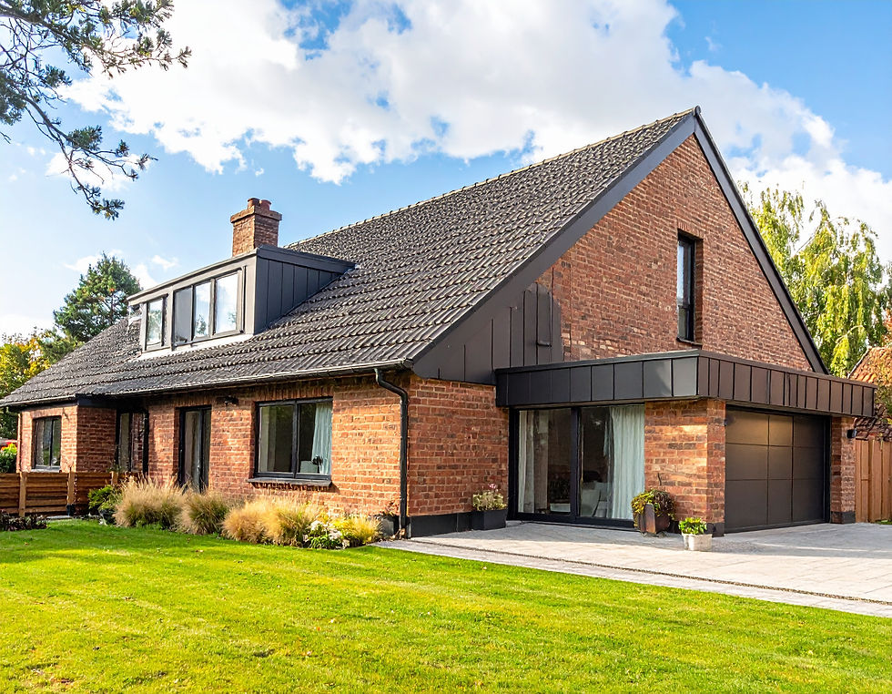Brick house with Flat‑roof dormer conversion set in a green garden under a blue sky. Potted plants line the entrance.