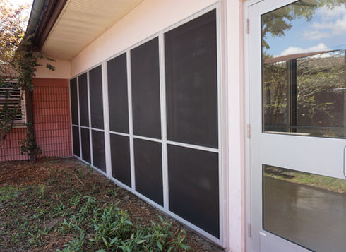 Building exterior with protective hurricane screens and white door