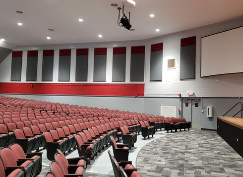 Empty school auditorium with red seats, and stage