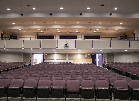 Empty auditorium with rows of purple seats and a full balcony