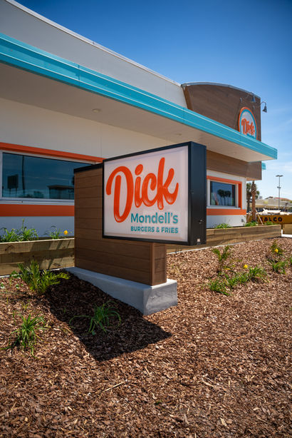 Dick Mandell's Burgers and Fries sign in front of restaurant building on sunny day