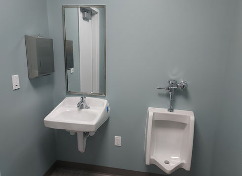 Warehouse restroom with sink, mirror, and urinal