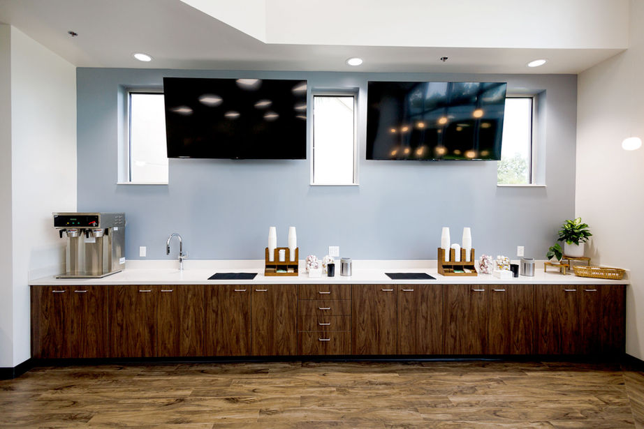 Hospitality area with two TVs, wooden cabinets, and white countertop.