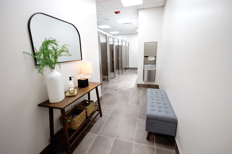 Modern bathroom with mirror, table, and bench along a hallway.