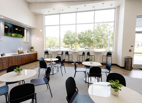 Multi-purpose church hospitality entry with cafe tables and large windows