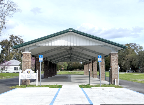 Civic pavilion with green roof, brick columns, paved entrance