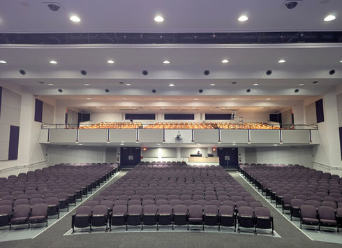 Empty auditorium with rows of purple seats and a balcony