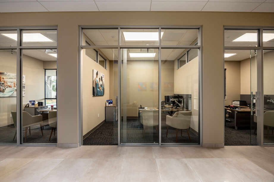 Modern office spaces with plenty of natural light, desks, computers, and chairs in each room