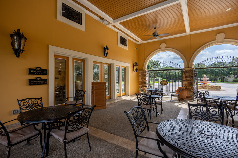 Outdoor restaurant seating area with tables and chairs near arched doorways.