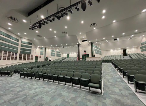 Large K-12 school auditorium with green seating