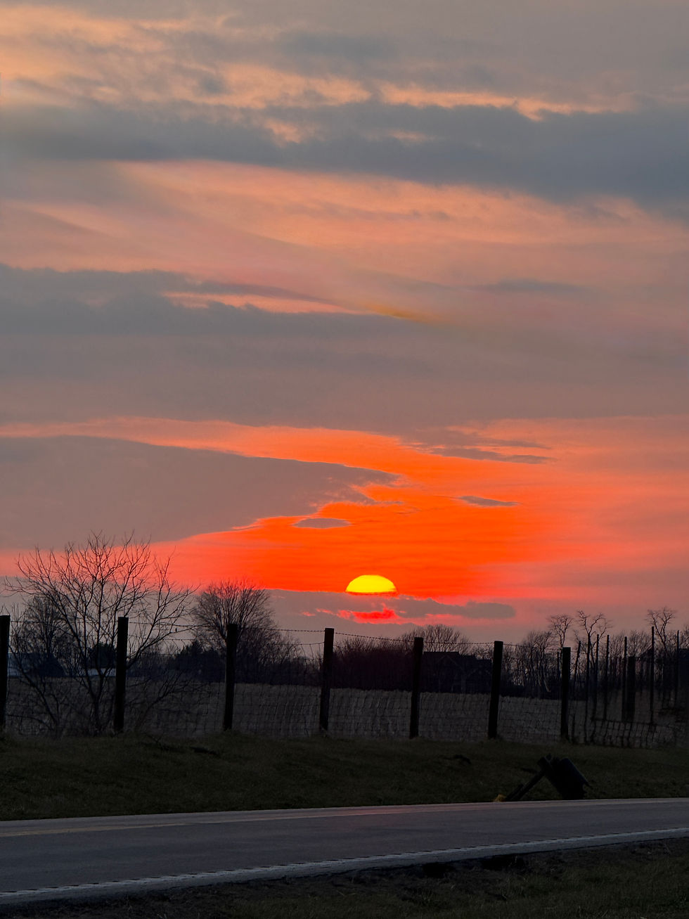 Brilliant orange sunset over a road and fence