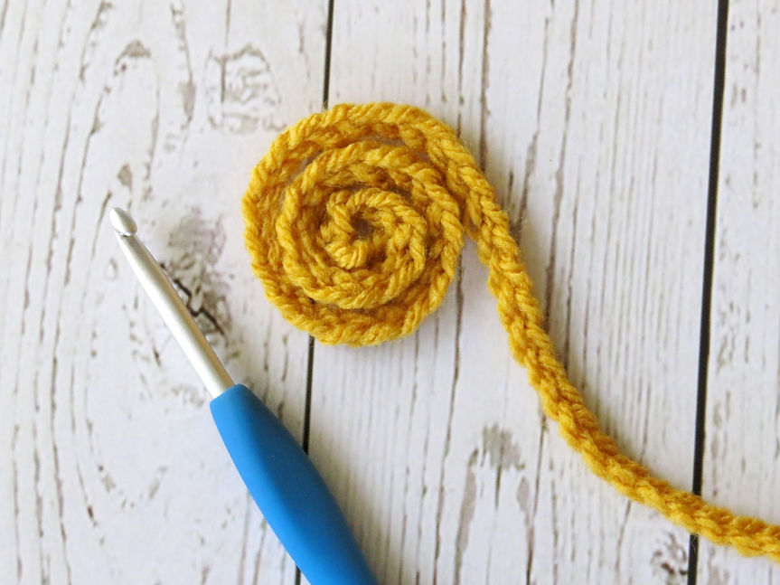 Crochet hook with gold yarn chain stitch in shape of koru