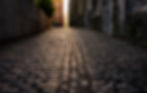 A photo of a cobblestone street in Dublin, Ireland at sunrise. The sun is shining off the 