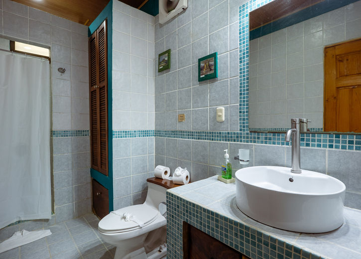 Bathroom with freestanding white basin, toilet, and teal mosaic tiles in the Tree Top Canopy room at Boutique Hotel Las Cascadas