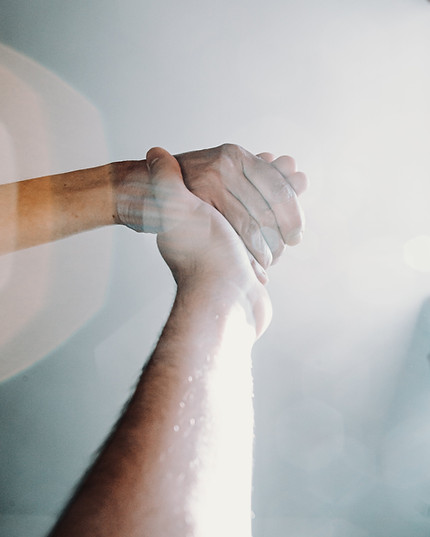 Two people holding each other's hands during a trauma therapy session.