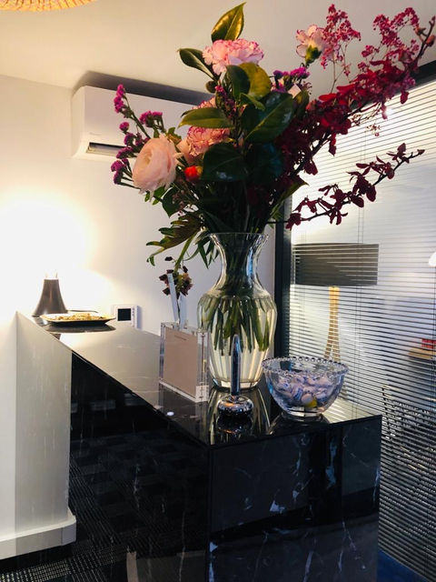 Comptoir d'accueil en marbre noir dans un cabinet d'avocats. Sur le comptoir se trouvent un bouquet de fleurs et la lampe pipistrello.