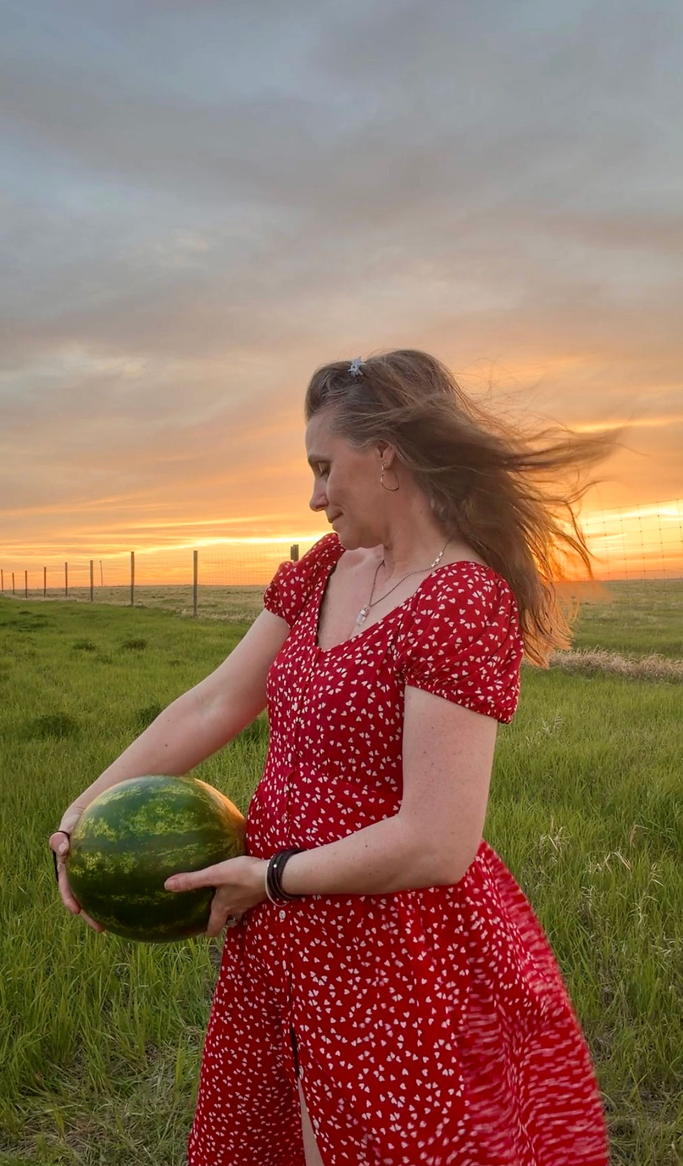 Woman looking down thoughtfully in a prairie field at sunset while reflecting on social anxiety, belonging, and the desire to feel safe enough to dance.