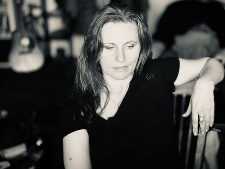 Black and white portrait of a woman sitting in quiet reflection, soft light and shadow creating a calm, introspective mood.