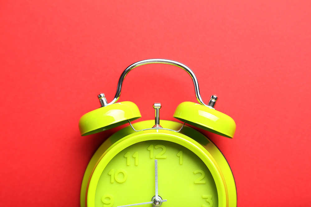 A yellow-green alarm clock on a white backdrop