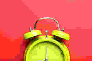 A yellow-green alarm clock on a white backdrop