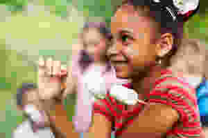 Little girl having fun at camp and roasting marshmallows