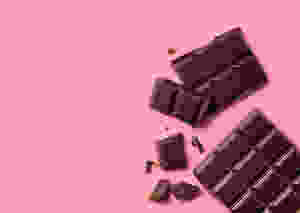 Dark chocolate squares on a pink background