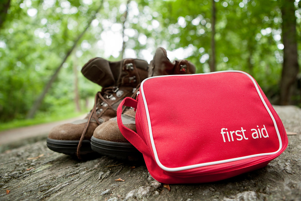 first aid kit next to a pair of hiking boots