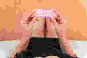 girl laying down and holding up hormonal birth control pills