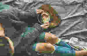 Girl in sweater and jeans sitting on her bed with something healthy