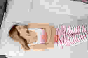 Woman in pain laying on her bed.
