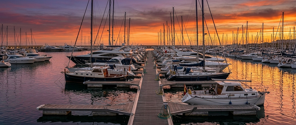 Puerto con vista de un pantalán lleno de barcos al atardecer